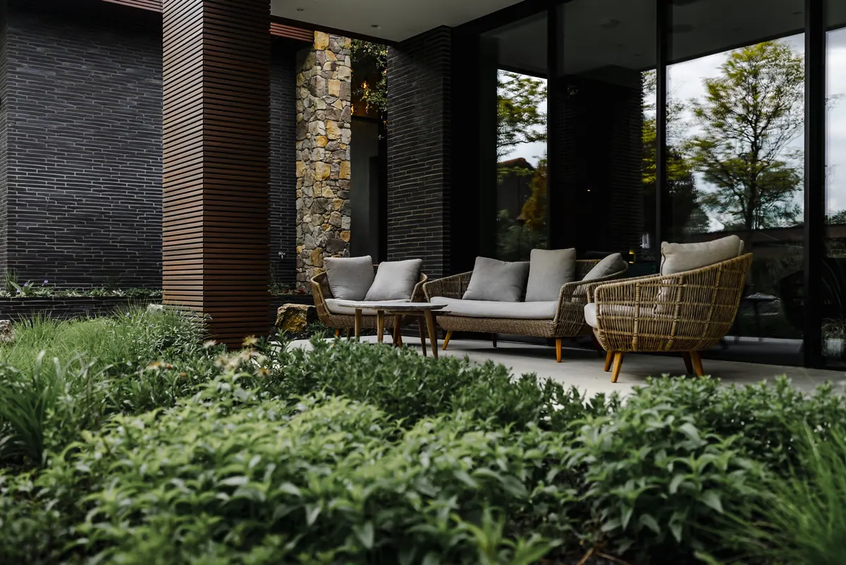 Overdekt terras met loungemeubels, op de voorgrond vaste planten