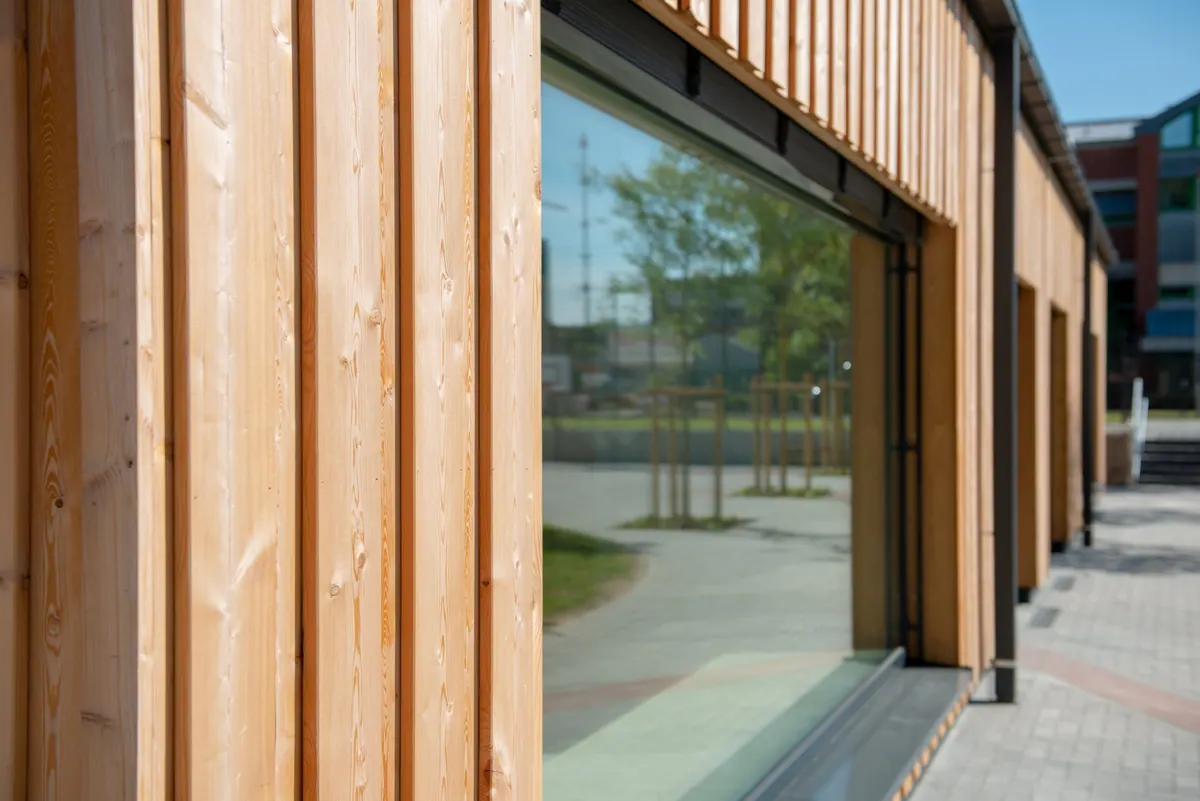 Detail der senkrechten Holzverschalung neben einem bodentiefen Fenster