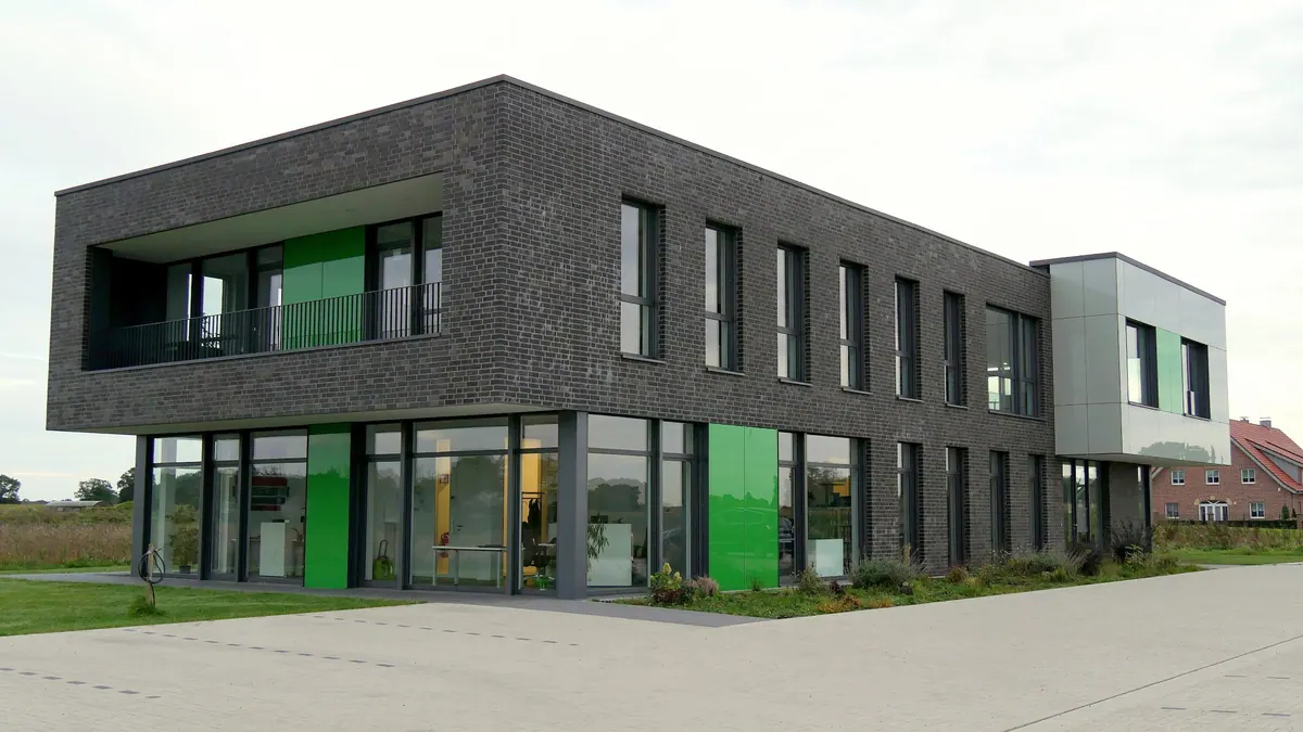 Bürogebäude Arpadis in Velen mit dunkler Klinkerfassade, auskragendem Obergeschoss und grünen Fassadenelementen