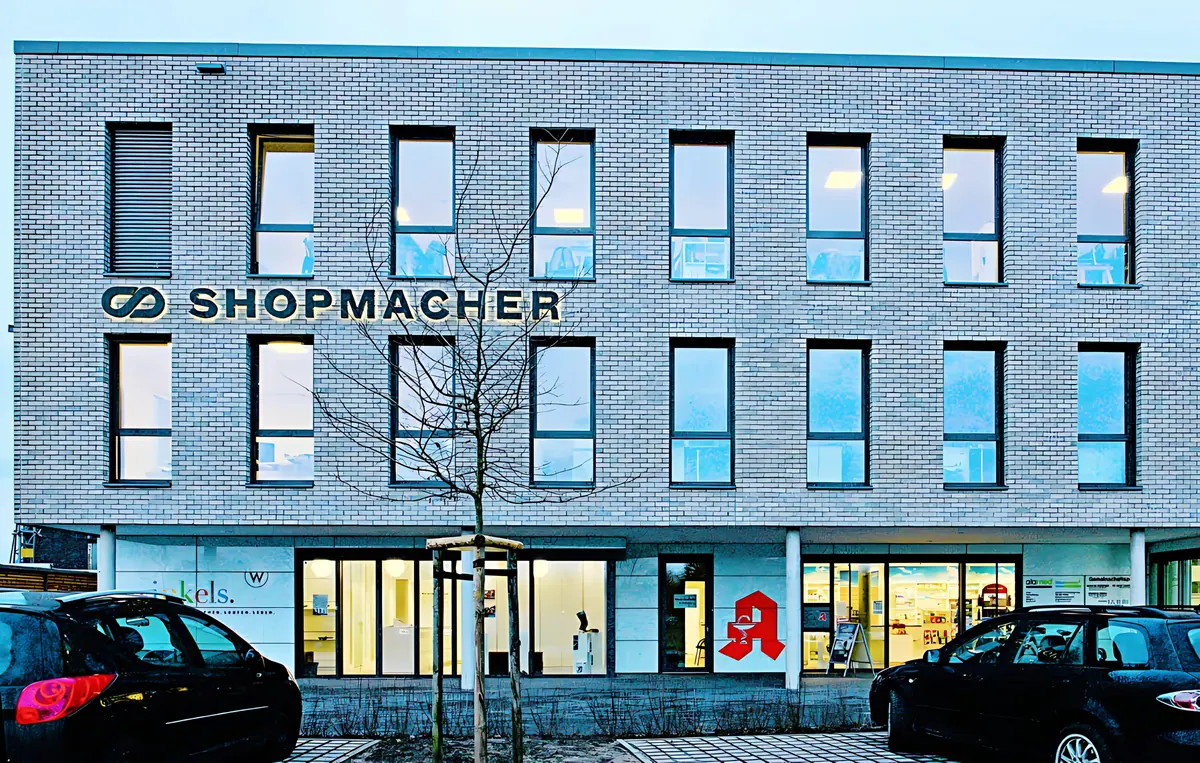 Hauptfassade des Gesundheitszentrums mit Lochfassade und Firmenschriftzug