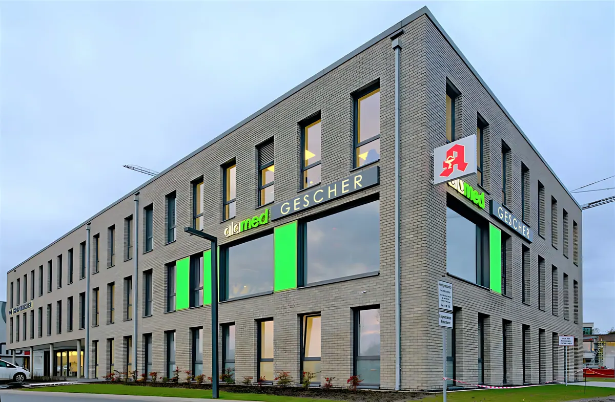 Gebäudeecke mit grün hinterleuchteten Glasflächen und Apothekenschild