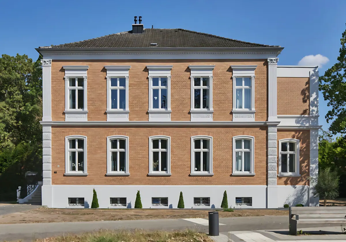 Straatgevel van de gerestaureerde villa met symmetrische rij ramen en entreebordes