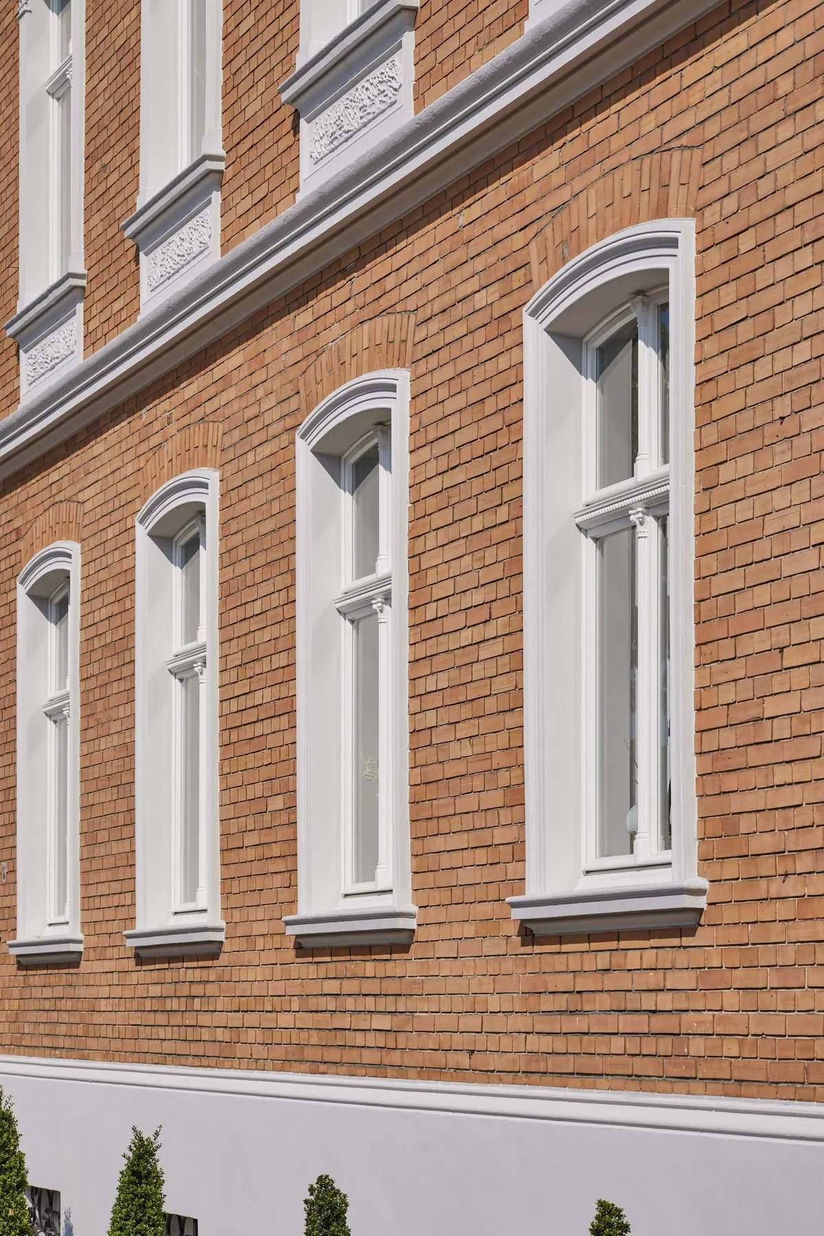 Geveldetail met geelbruine baksteen en wit geschilderde raamomlijstingen