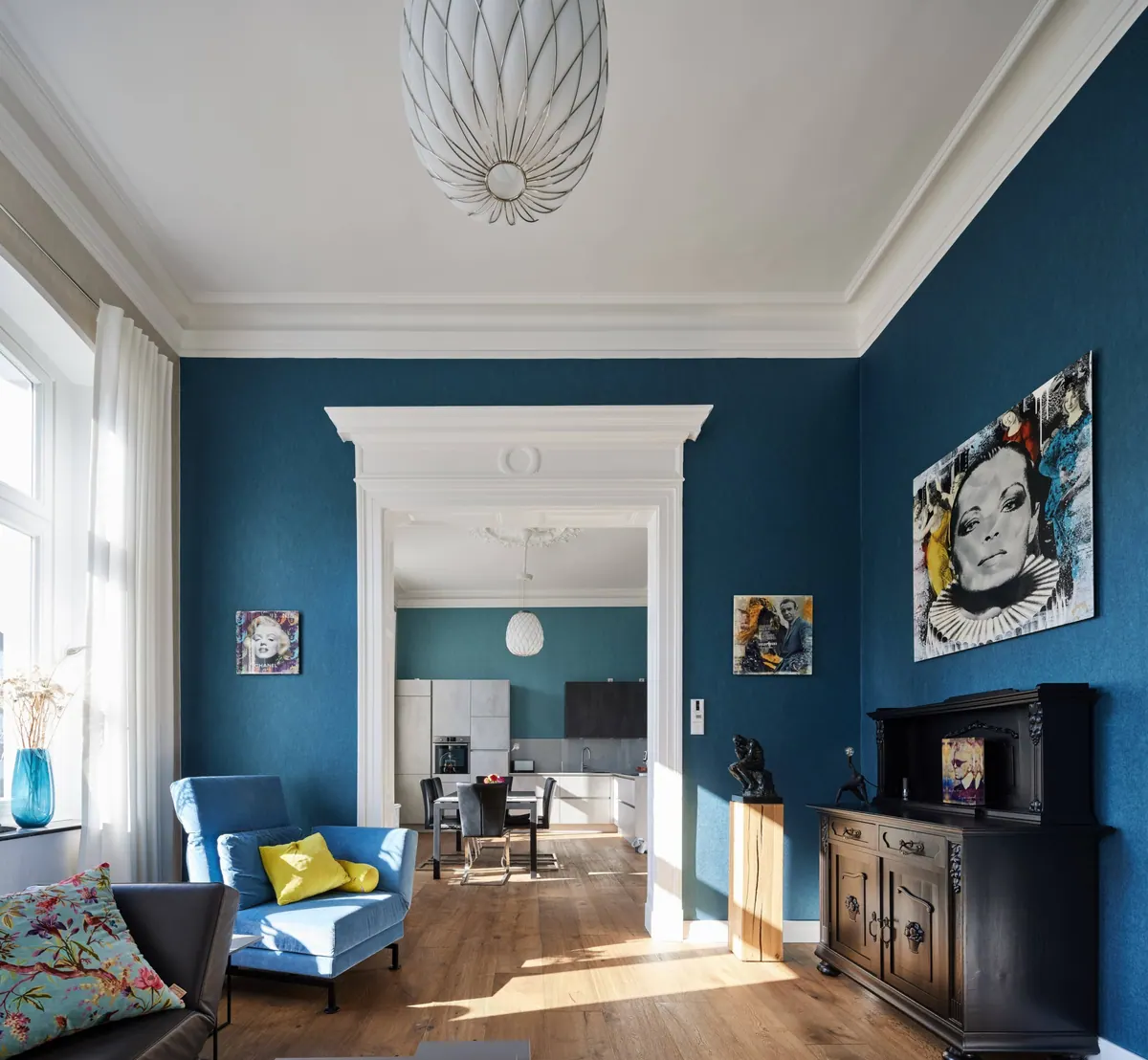 Petrolblauw geschilderde kamer met plafondrozet, kunst aan de wand en fauteuils