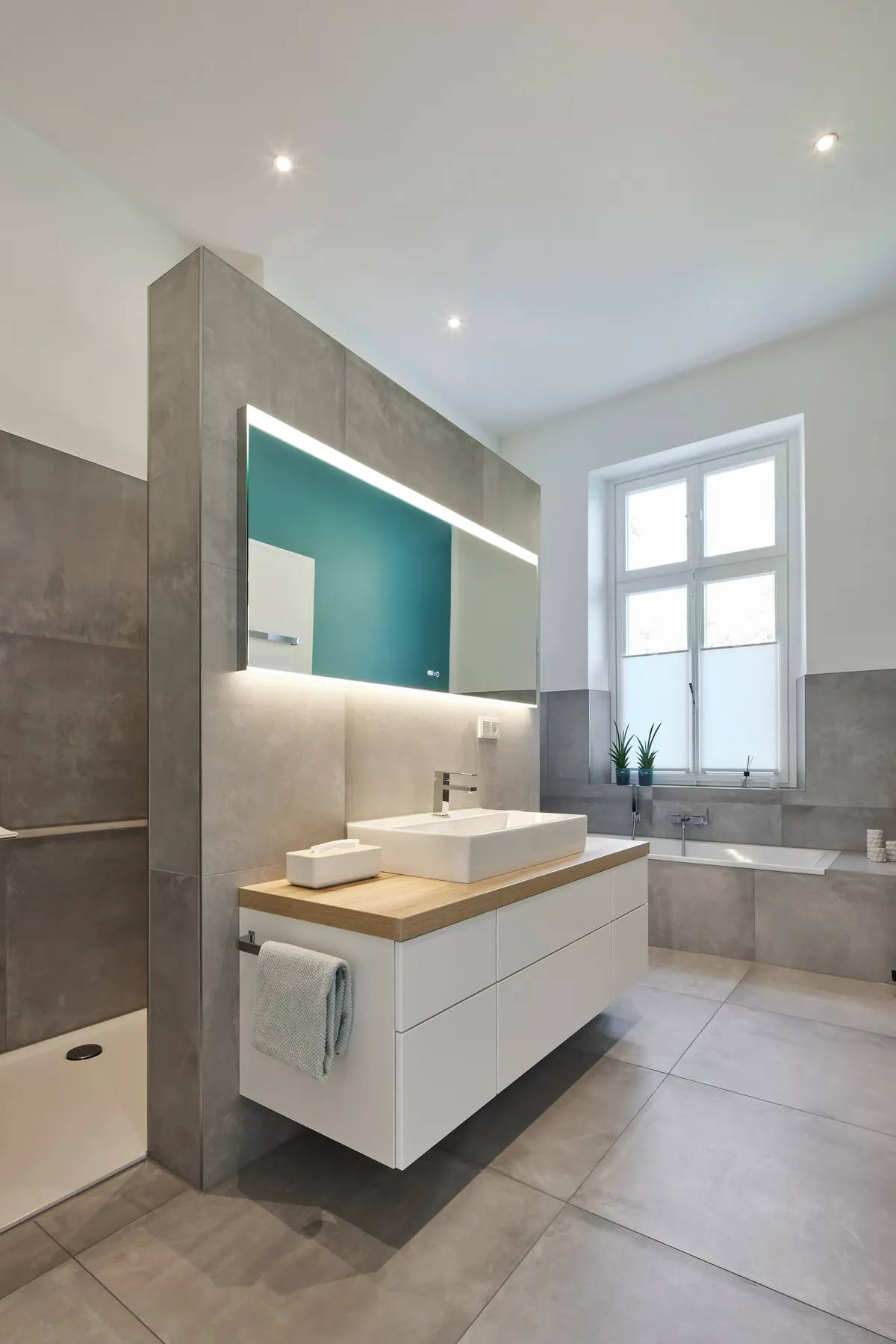 Moderne badkamer in het oude pand met wastafel, vrijstaande wand en hoog raam