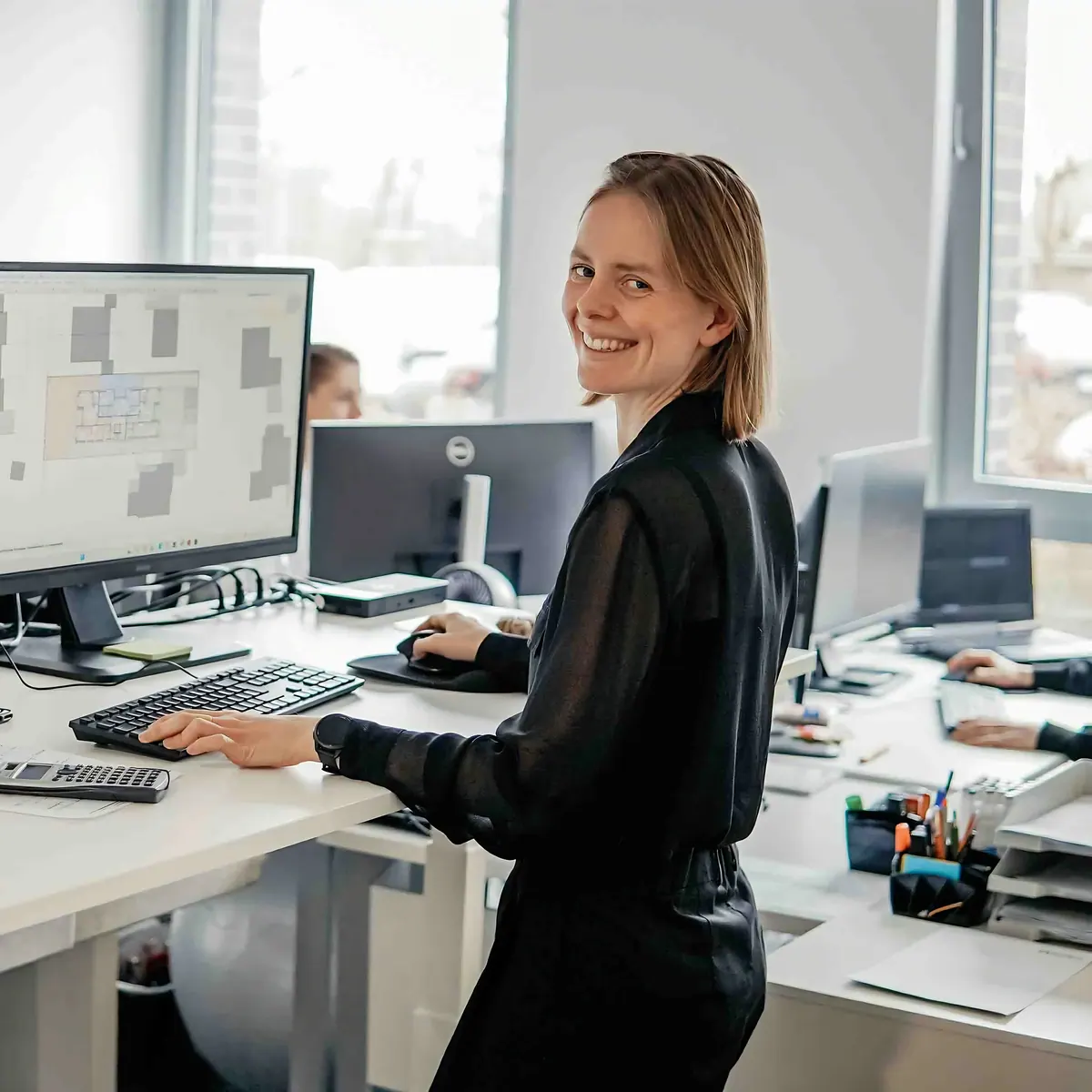 Een collega werkt aan een zit-stabureau met twee beeldschermen