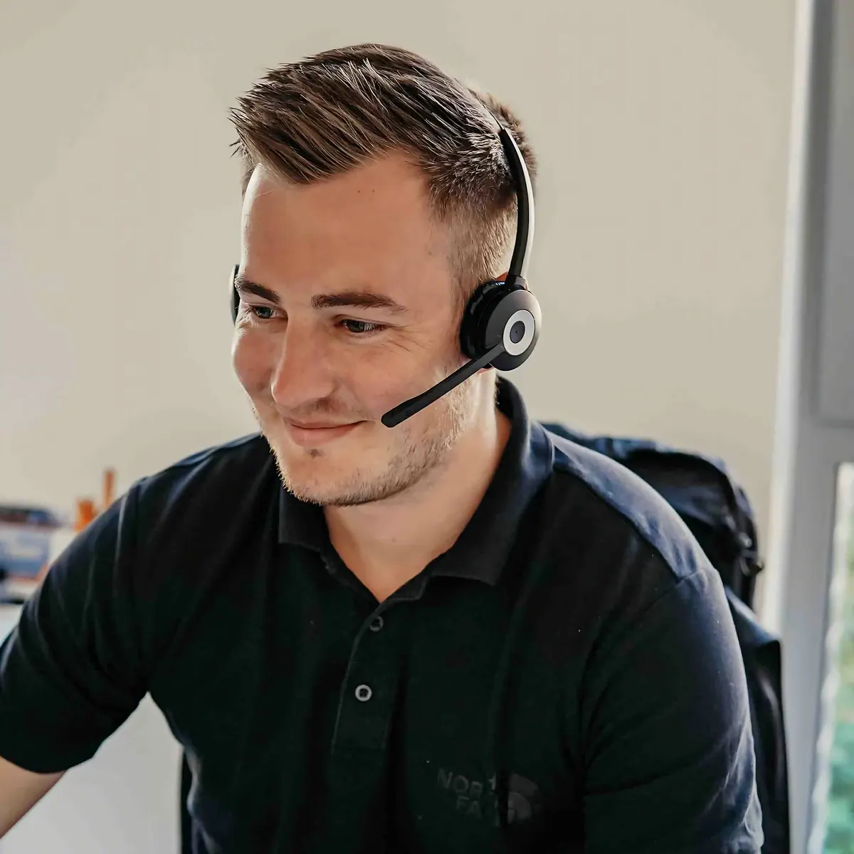 Een collega belt met een headset op zijn werkplek
