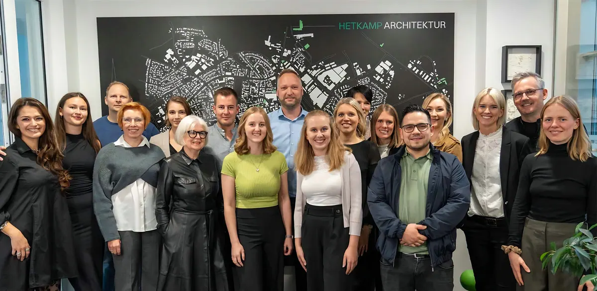 Das Team von Hetkamp Architektur im Büro vor einer großen Stadtkarte